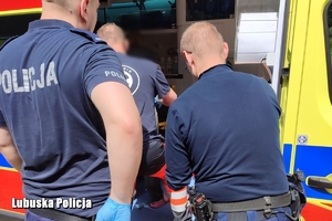 policjanci i medycy stoją przy karetce