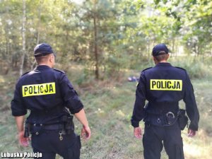 Na fotografii widać dwóch policjantów, którzy dyskutują, będąc na terenie przeszukania.