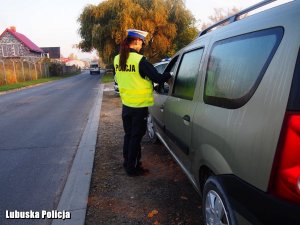 Na zdjęciu widzimy policjantkę legitymującą kierowce samochodu.