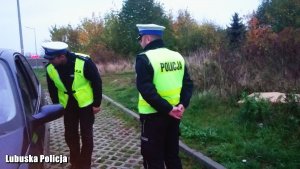 Na zdjęciu widać dwóch policjantów, którzy dokonują kontroli kierowcy.