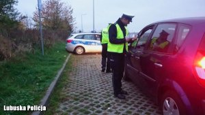 Na zdjęciu są dwaj policjanci dokonujący rutynowej kontroli kierowcy i jego pojazdu.