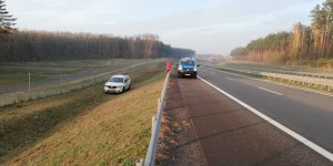 Zdjęcie przedstawia samochód, który wypadł z drogi ekspresowej S3. W tle widoczny także policyjny bus stojący na pasie awaryjnym.