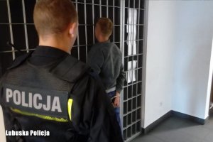 Policjant oraz zatrzymany przy kratach celi przejściowej