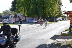 biegnący uczestnicy biegu, przed nimi motocykl policyjny