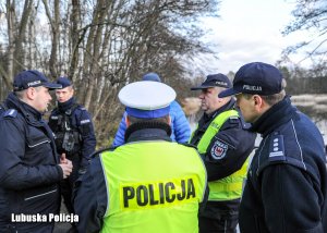 stojący umundurowani policjanci na drodze przy rozlewisku