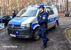 policyjny radiowóz, przy którym stoi policjant