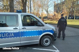 Policjant i radiowóz na tle parku