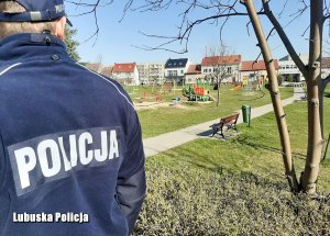 policjant stojący tyłem, w tle park