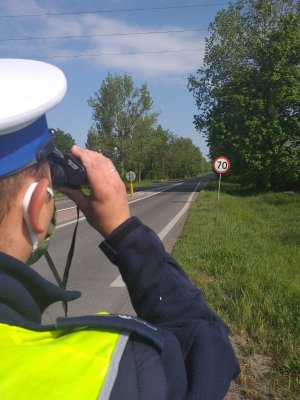 policjant spoglądający przez lornetkę na nadjeżdżające pojazdy