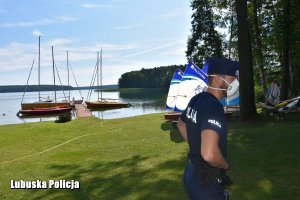 Policjant na trawiastej plaży w tle łodzie