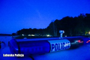 Policjant na łodzi sprawdza linie brzegową jeziora przy ośrodku w nocy