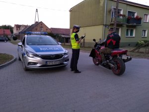 Policjantka kontroluje motocyklistę w tle z lewej radiowóz