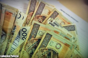 Banknoty 200 złotowe rozłożone a tle biurko i dokumentacja