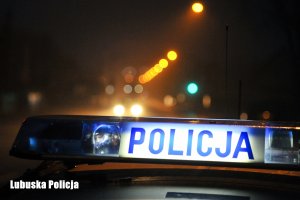 Sygnalizacja radiowozu na dachu z napisem Policja, w tle noc