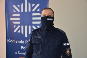 Umundurowany policjant stojący w pomieszczeniu, za plecami widoczny jest rollup z logiem policji i napisem Komenda Powiatowa Policji  w Świebodzinie