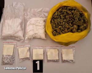 Na blacie leży duży żółty worek z marihuaną, woreczki strunowe z tabletkami MDMA Extasy oraz oraz dwa woreczki z bryłami amfetaminy.