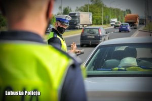 Policjant z ruchu drogowego na tle jadących pojazdów