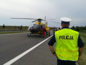 widok na startujacy śmigłowiec, w pierwszej linii policjant