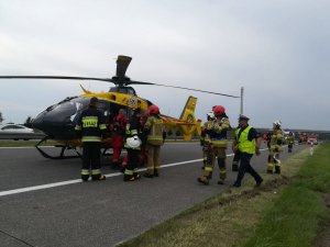 Służby ratownicze przy helikopterze stojącym na jezdni