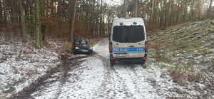 Leśna, zaśnieżona droga na której stoją dwa pojazdy. Cywilny opel astra oraz oznakowany radiowóz. Radiowóz stoi tyłem, osobówka przodem. Ślady wskazują na to, że opel obróci się wokół własnej osi.