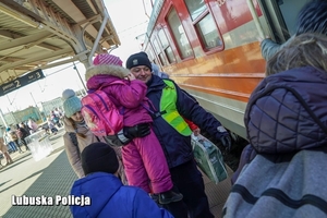 Policjant na peronie niosący dziecko