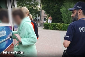 kobieta w asyście policji i ratownika medycznego wsiada do karetki