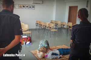 Policjanci patrzą na udzielanie pierwszej pomocy przez ucznia