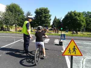 Policjant oceniający jazdę na rowerze ucznia podczas egzaminu na kartę rowerową