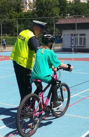 Policjant oceniający jazdę na rowerze ucznia podczas egzaminu na kartę rowerową