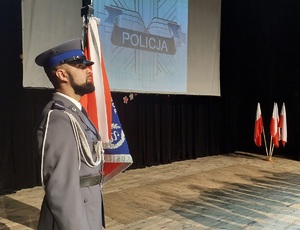 Poczet sztandarowy, w tle wyświetlone logo policji