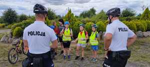 Policjanci rozmawiają z dziećmi, w tle rowery