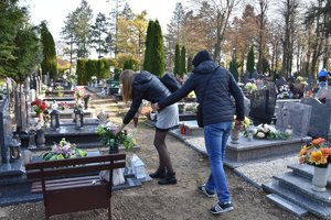 Zakapturzony mężczyzna podchodzący do kobiety na cmentarzu