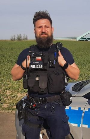 Policjant na tle wiaduktu przy radiowozie