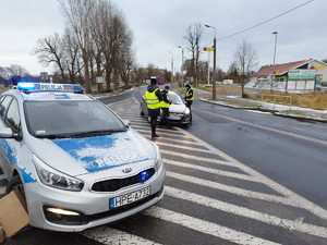 droga, radiowóz, w tle członkowie Komisji i dzielnicowi wspólnie dokonują kontroli.