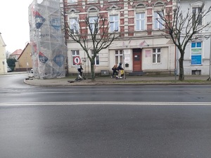 ulica, za nią chodnik, na nim 3 osoby na hulajnogach w zakazanym miejscu