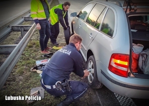 Policjanci przy pojeździe pomagają przykręcić koło