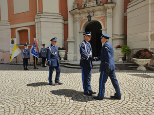 Dowódca uroczystości składa meldunek Komendantowi Wojewódzkiemu, w tle kościół i poczet sztandarowy.