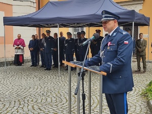 Komendant przemawia przy mównicy, w tle zaproszeni goście