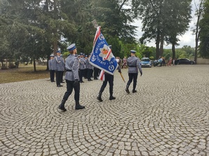 Odprowadzenie pocztu sztandarowego, w tle policjanci wyróżnieni podczas święta.