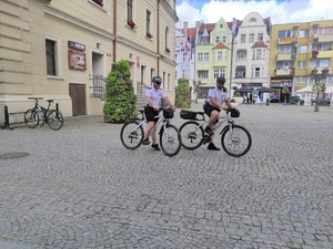 Dwaj policjanci na rowerach w centrum miasta.