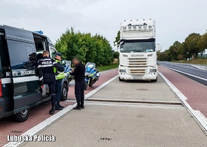 Bus Inspekcji Transportu Drogowego, obok ich funkcjonariusz, policjant i kierowca. W tle ciężarówka.