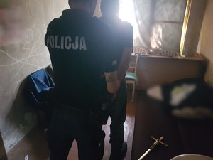 W pomieszczeniu policjant zakuwa w kajdanki meżczyznę