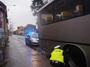 Policjantka sprawdza koła autokaru, z tyłu radiowóz