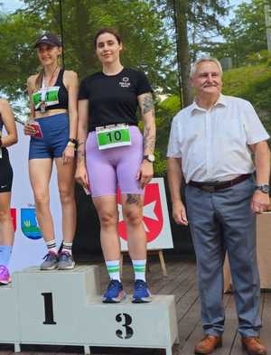 Dwie kobiety na podium oraz mężczyzna stojący obok