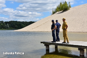 Policjanci i strażak na pomoście nad wodą