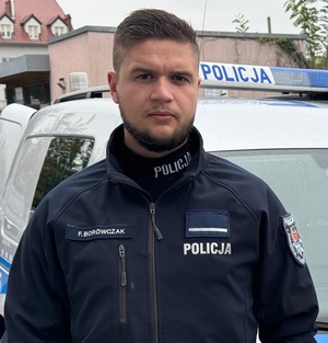 Policjant od pasa w górę na tle radiowozu