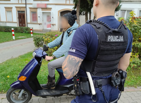 Kobieta na motorowerze, obok policjant