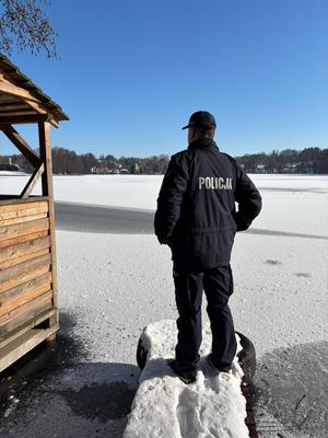 Policjant na kładce nad zamarzniętym jeziorem