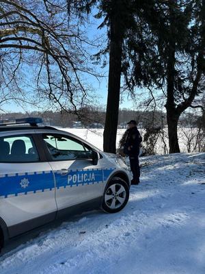 Policjant i radiowóz przy zamarzniętym jeziorze