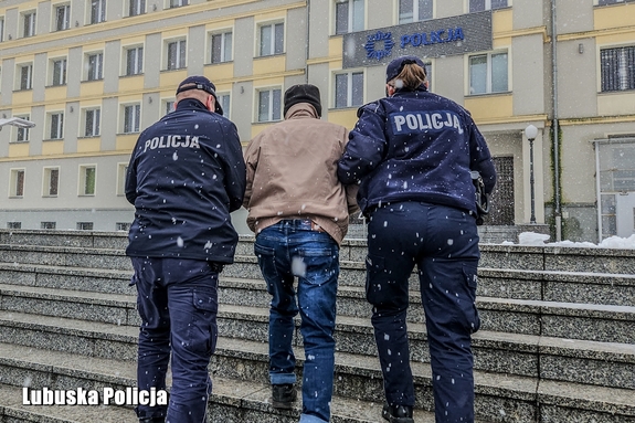 Policjanci prowadzą zatrzymana osobę